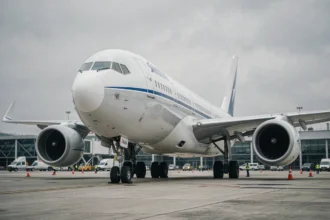 Vue en contre-plongée d'un avion de ligne moderne sur le tarmac d'un aéroport international, montrant la puissance et l'envergure de l'appareil