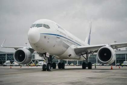 Vue en contre-plongée d'un avion de ligne moderne sur le tarmac d'un aéroport international, montrant la puissance et l'envergure de l'appareil